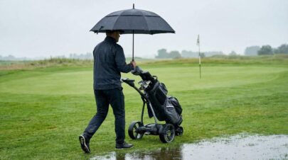 golfparaply i brug med golfvogn på golfbane i regnvejr
