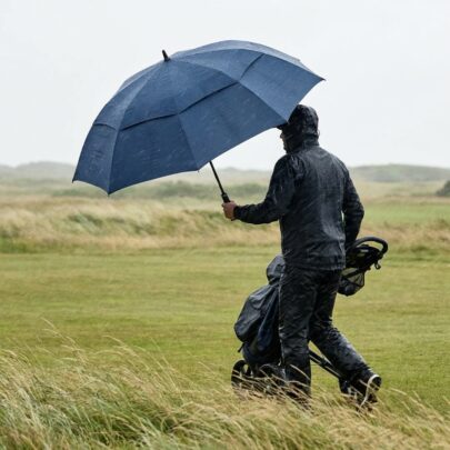 starkt paraply i kraftig vind på golfbana